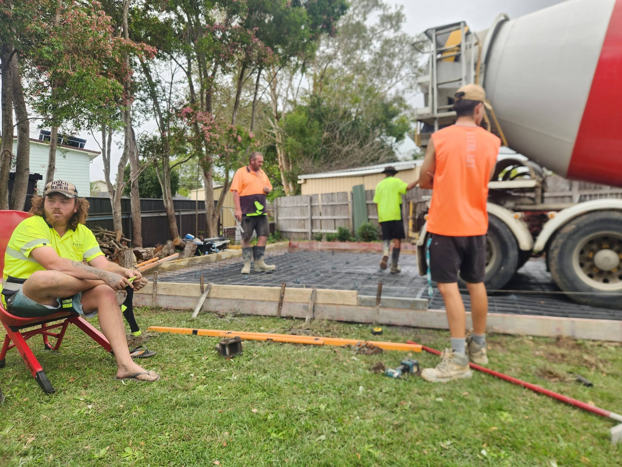 Crew and agitator truck pouring a shed slab over steel mesh